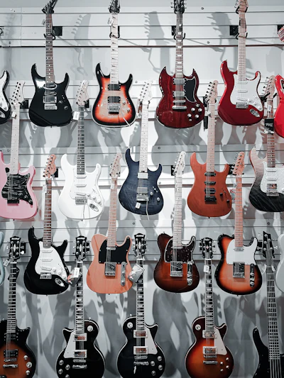 Diversas guitarras elétricas de formatos diferentes penduradas em uma parede de loja