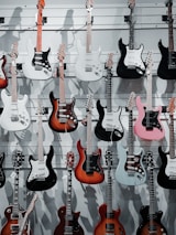 A variety of colorful guitars hanging on the wall, inviting customers to try them.