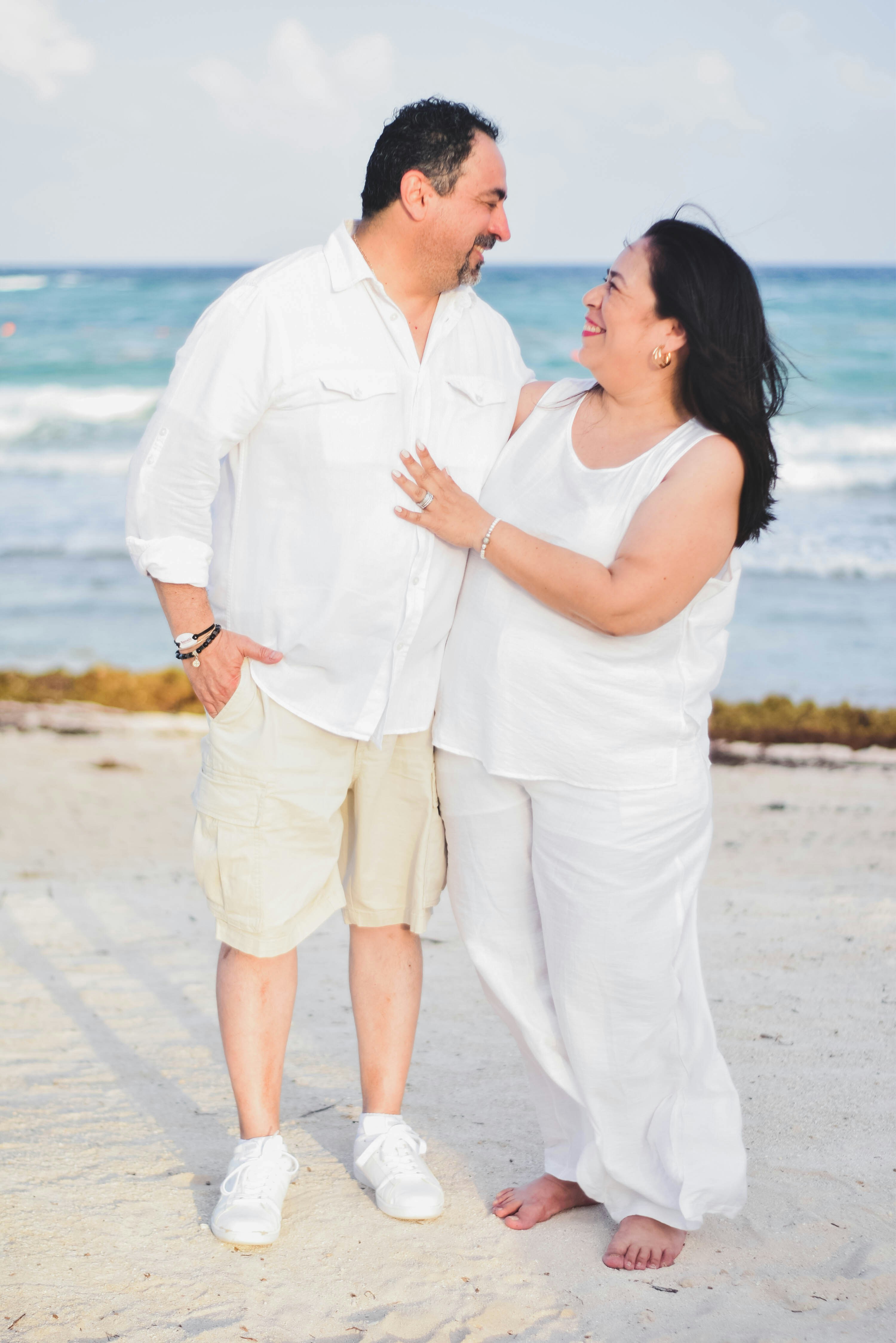 a man and woman standing on a beach next to the ocean