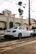 A sleek silver sedan parked on a sunny Cancún street with palm trees in the background