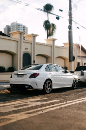 Elegant white executive vehicle waiting curbside with city lights in the background
