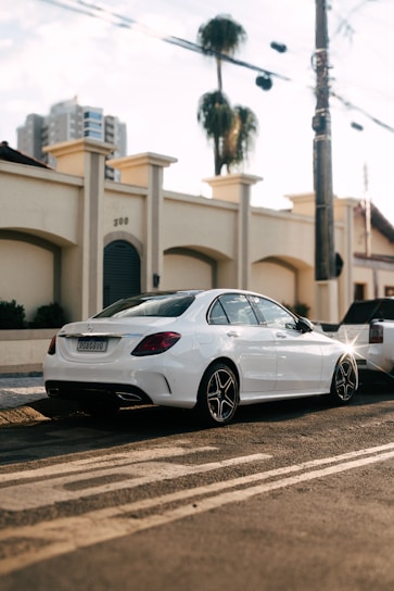Luxury sedan parked in front of a modern cityscape at dusk.