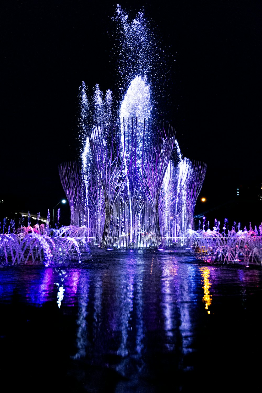 a water fountain is lit up at night