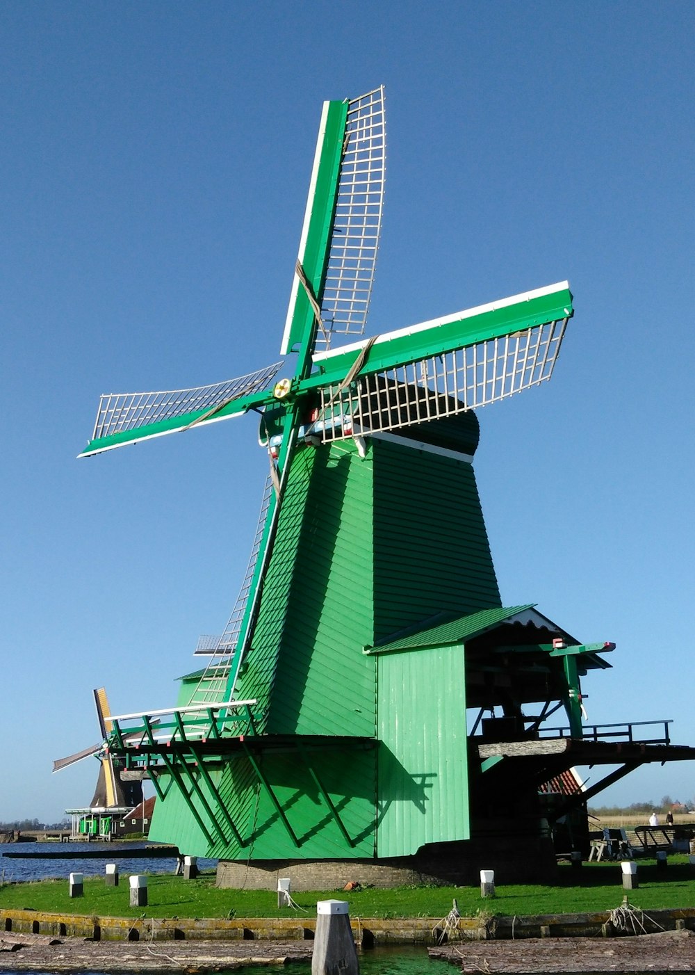 a green windmill sitting next to a body of water