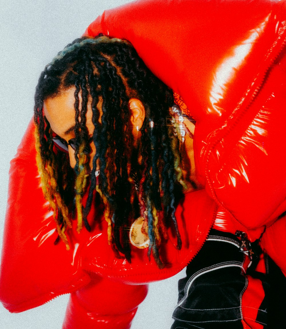 a man with dreadlocks wearing a red jacket