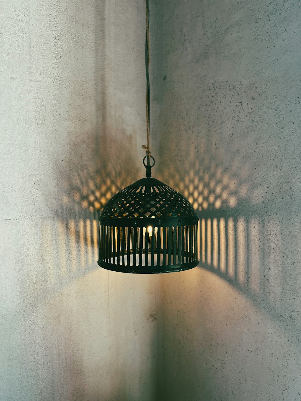 a birdcage hanging from a wall with a light shining on it