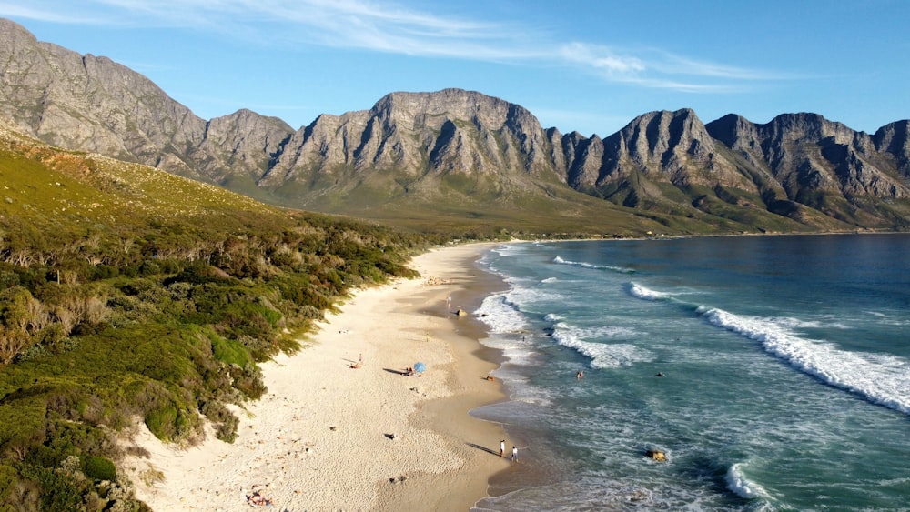 an aerial view of a beach with mountains in the background