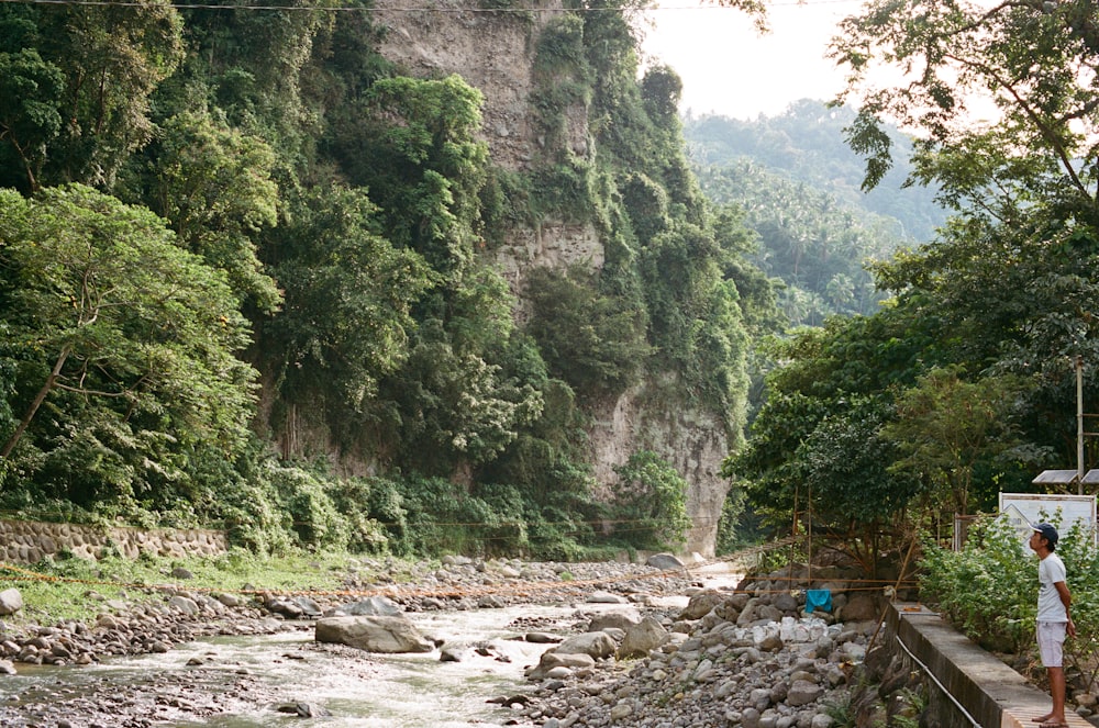 a man standing on a bridge next to a river