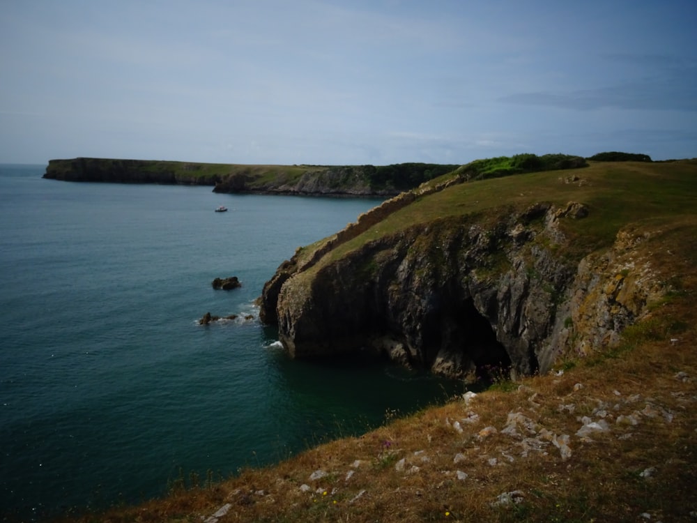 a large body of water sitting next to a lush green hillside