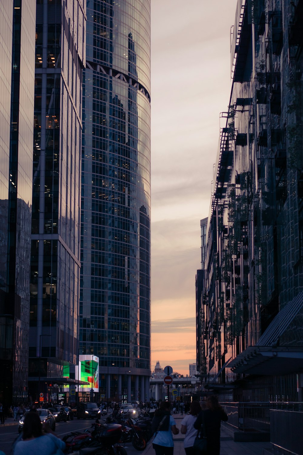 a group of people walking down a street next to tall buildings