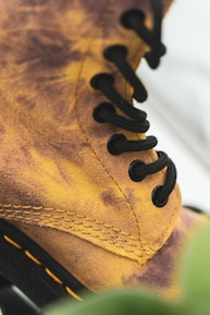 Close-up of hands examining the stitching and materials of a rugged boot under natural light.