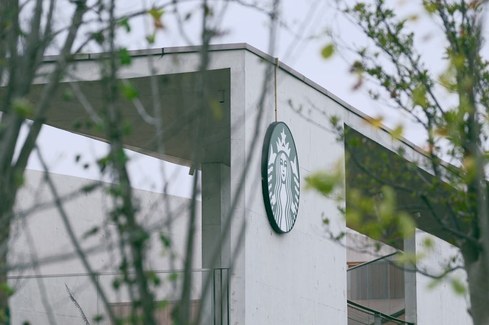 a starbucks sign is seen through the branches of a tree