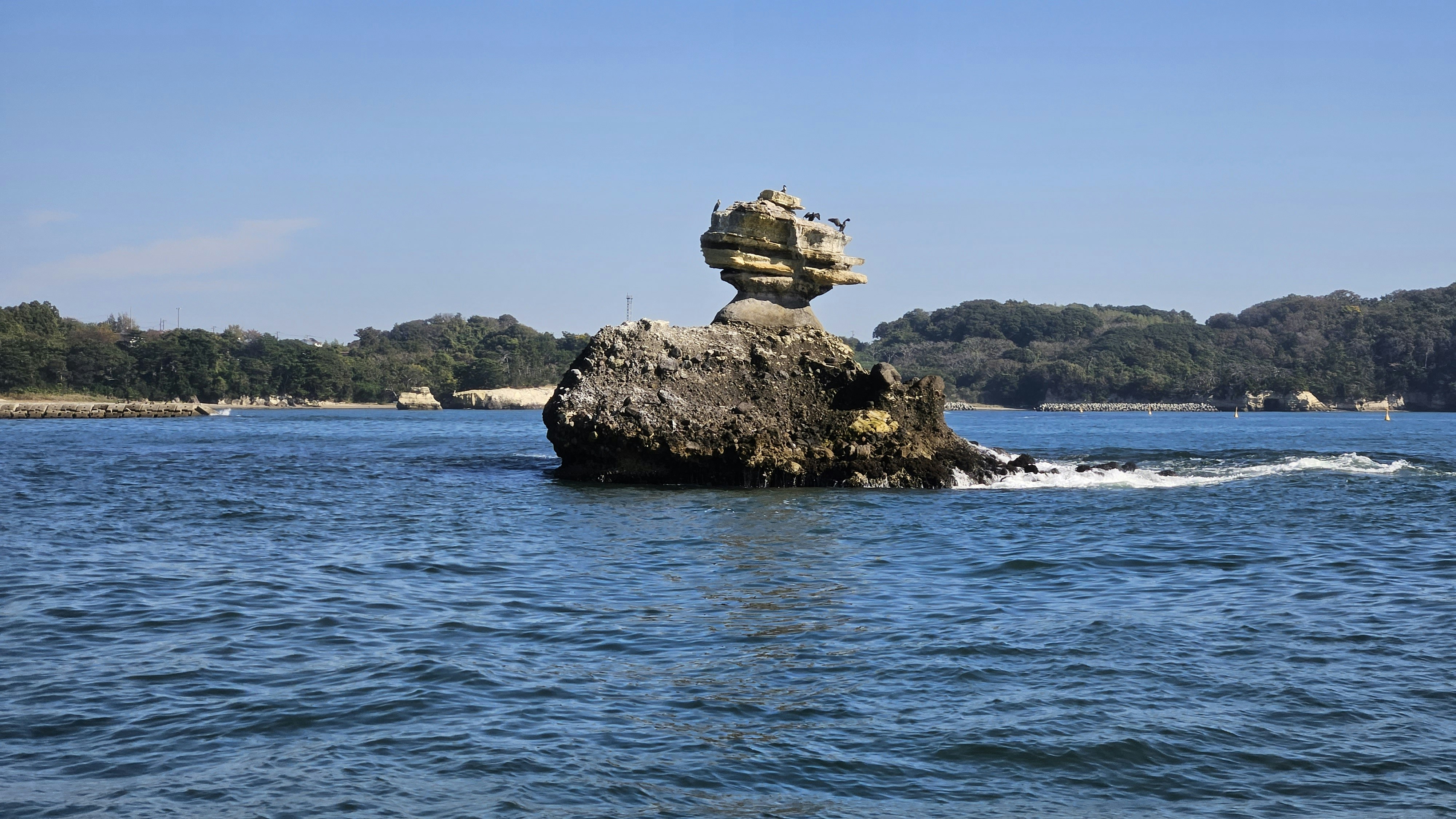 une formation rocheuse au milieu d’un plan d’eau