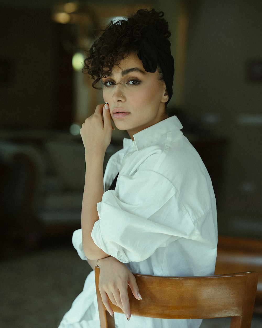 a woman sitting in a chair with her hand on her chin