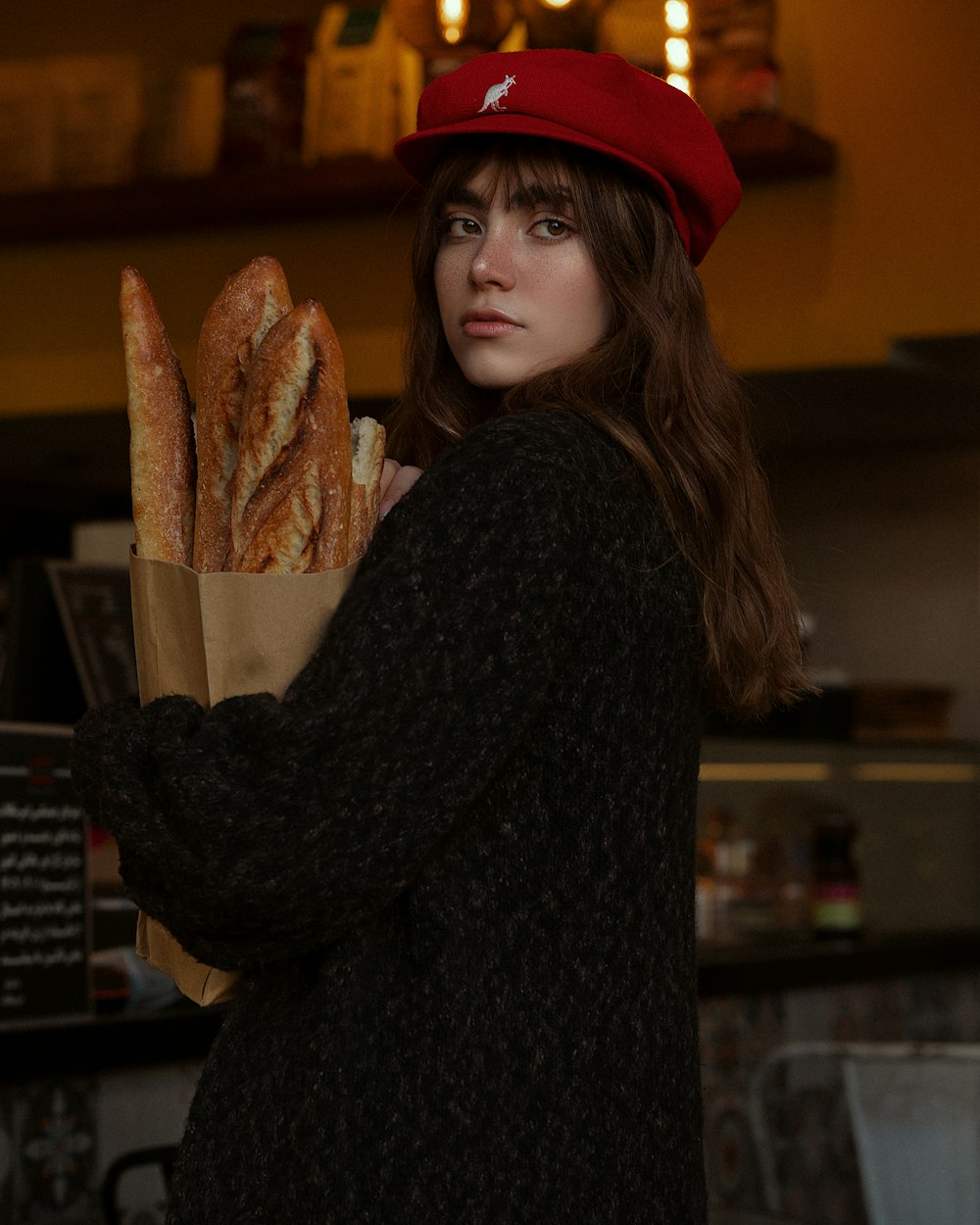 a woman in a red hat holding a bag of bread