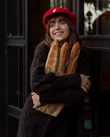A smiling customer holding a paper bag with freshly baked pastries outside the bakery.
