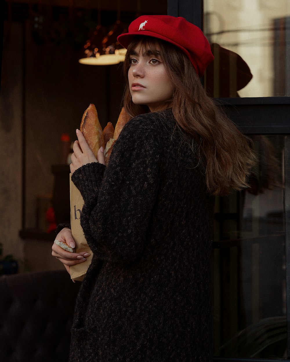 a woman in a red hat is holding a sandwich