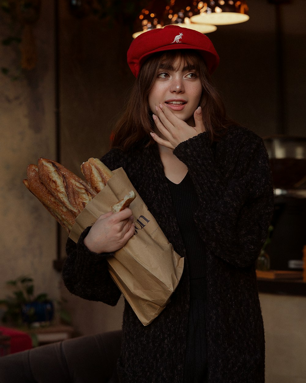 a woman in a red hat holding a bag of bread