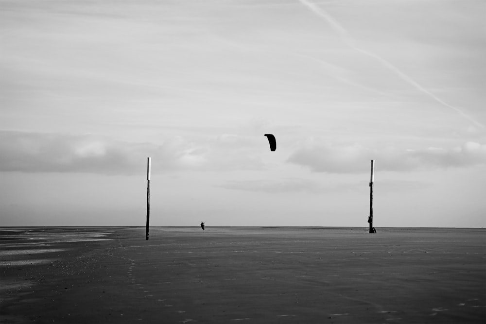 a black and white photo of a person flying a kite