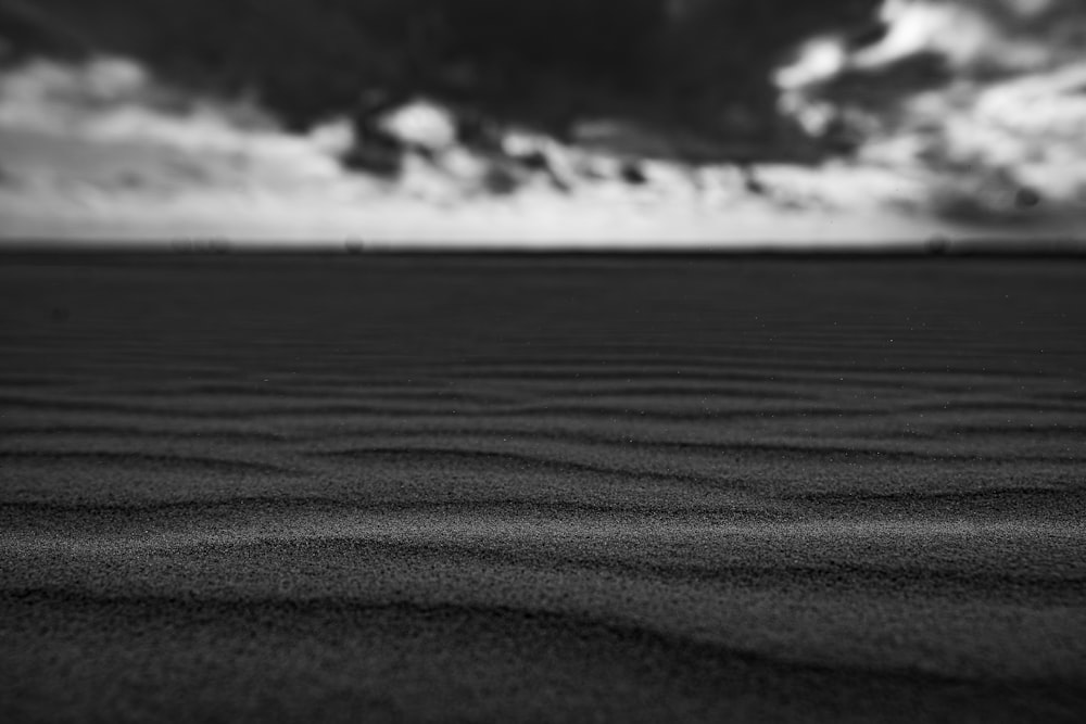 a black and white photo of sand and clouds