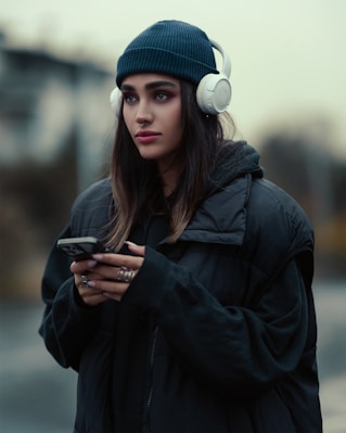 a woman wearing headphones is looking at her cell phone