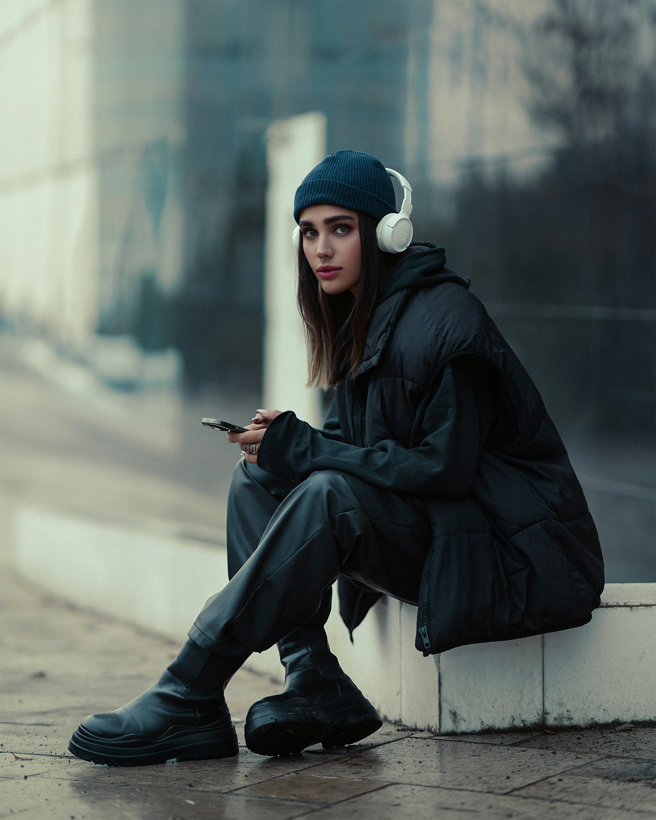 a woman sitting on a curb looking at her cell phone