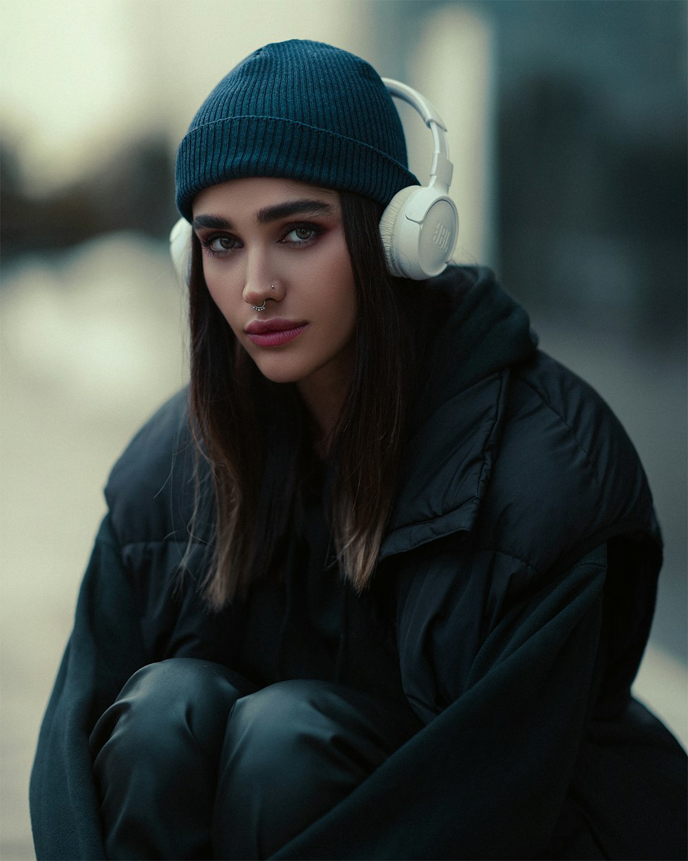 a woman with headphones sitting on a curb