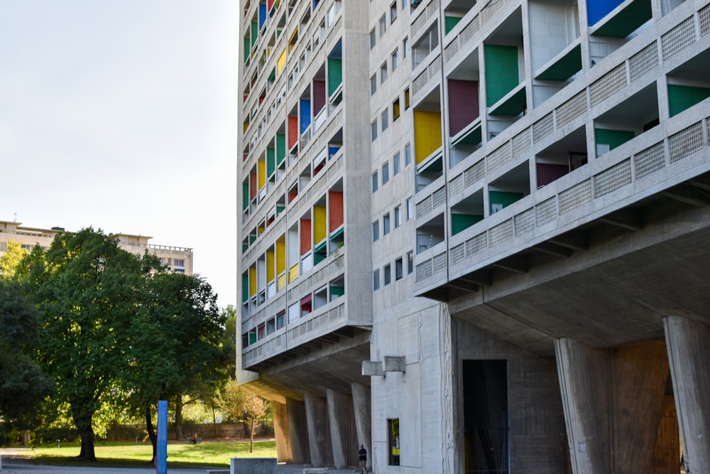 a tall building with multicolored windows next to a park