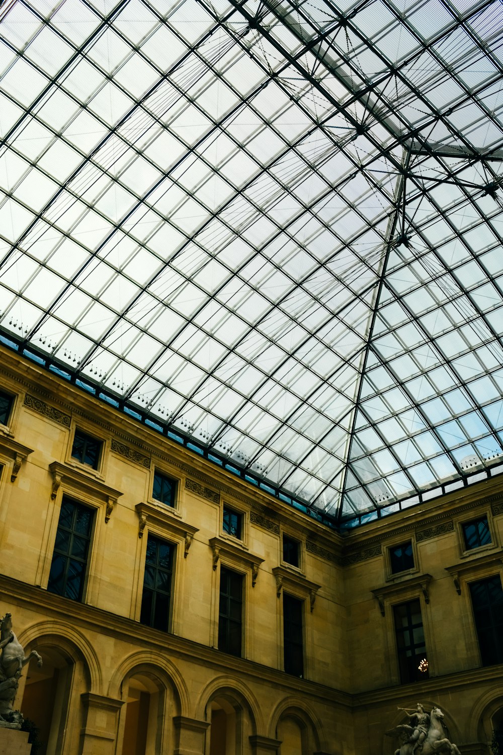 um teto de vidro em um edifício com estátuas