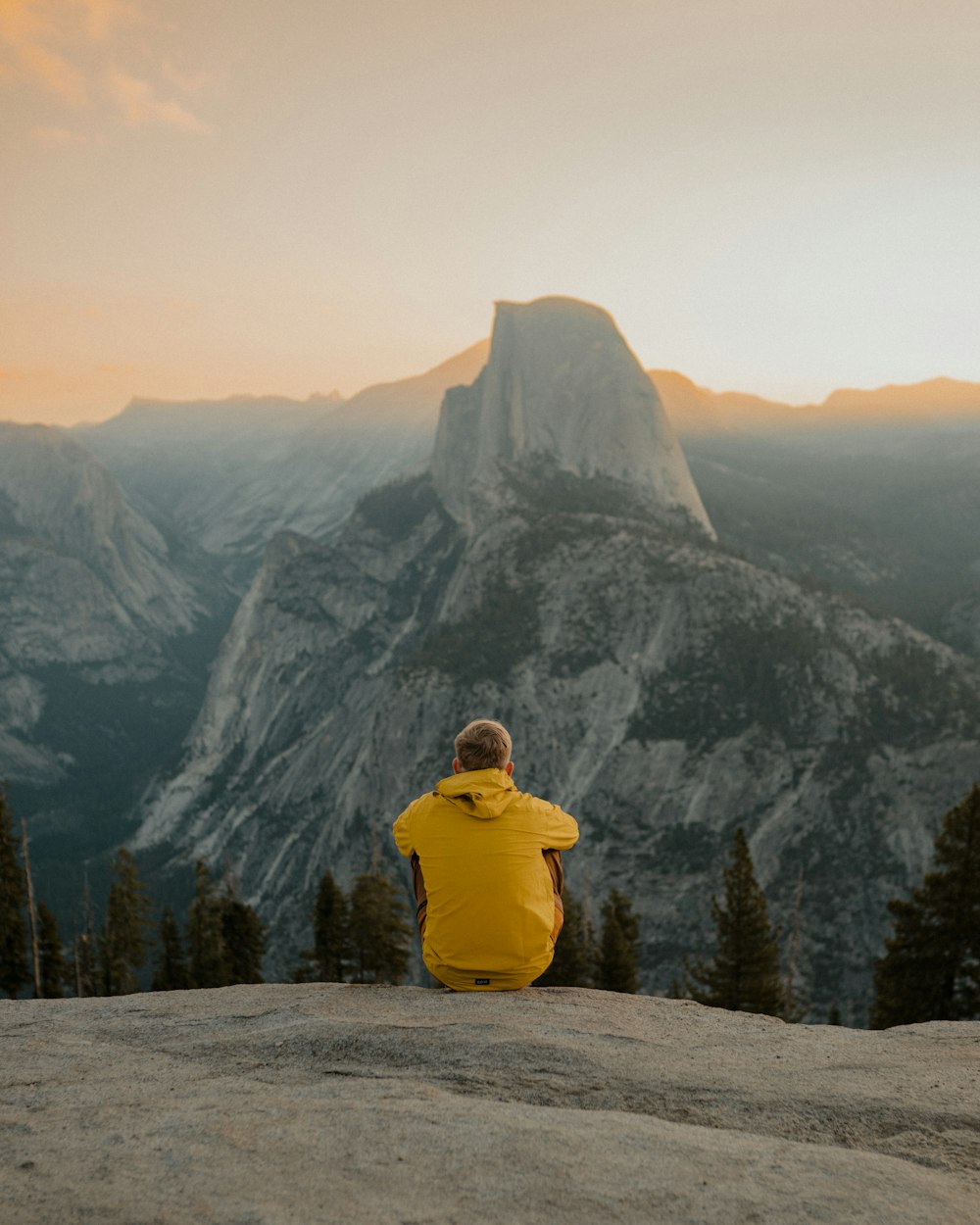 a person in a yellow jacket sitting on top of a mountain
