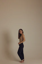 A serene model wearing the duality activewear set, standing barefoot on a sunlit wooden floor with soft shadows playing around.