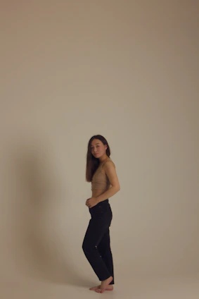 A serene model wearing the duality activewear set, standing barefoot on a sunlit wooden floor with soft shadows playing around.