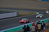 Wide-angle view of a Stock Car race start, cars lined up with flags waving and fans cheering in the background.