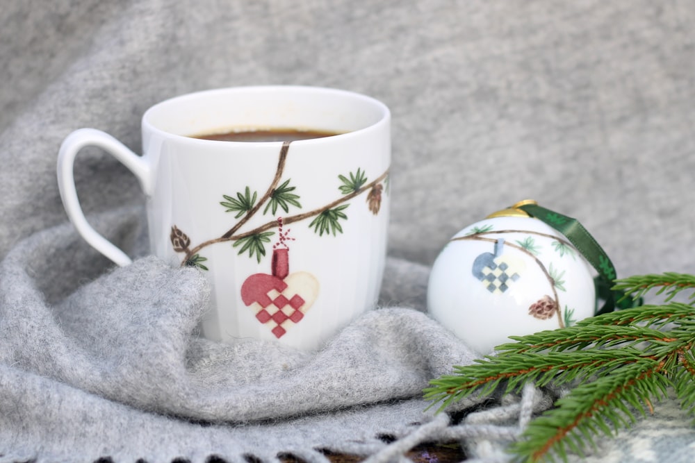 a cup of coffee next to a christmas ornament