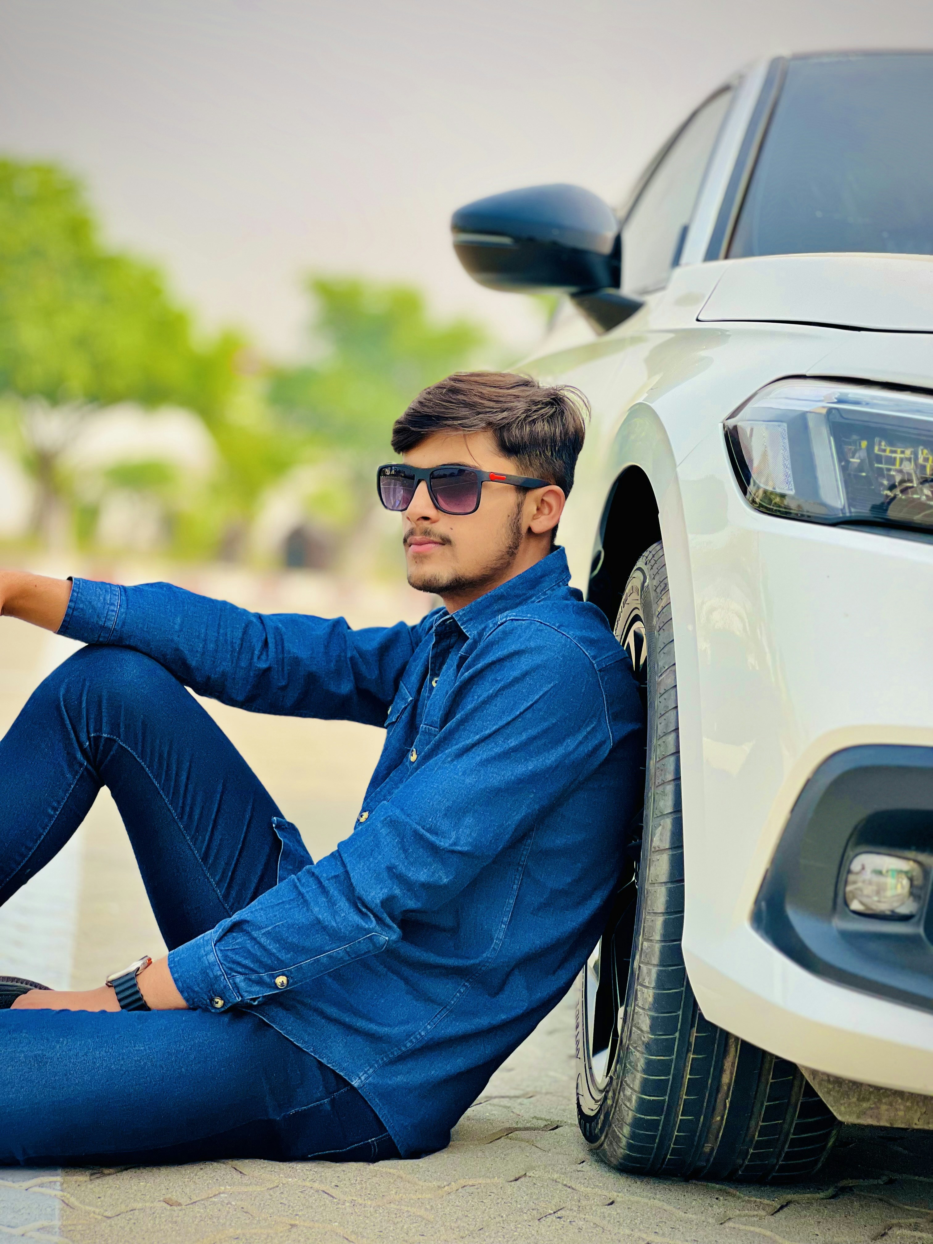a man sitting on the ground next to a car