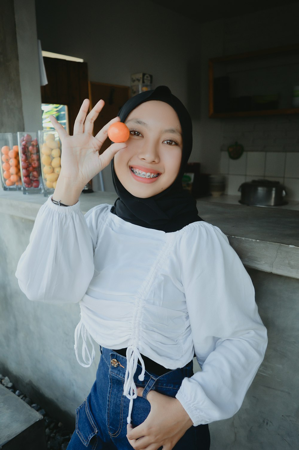 uma mulher em um hijab está segurando uma laranja