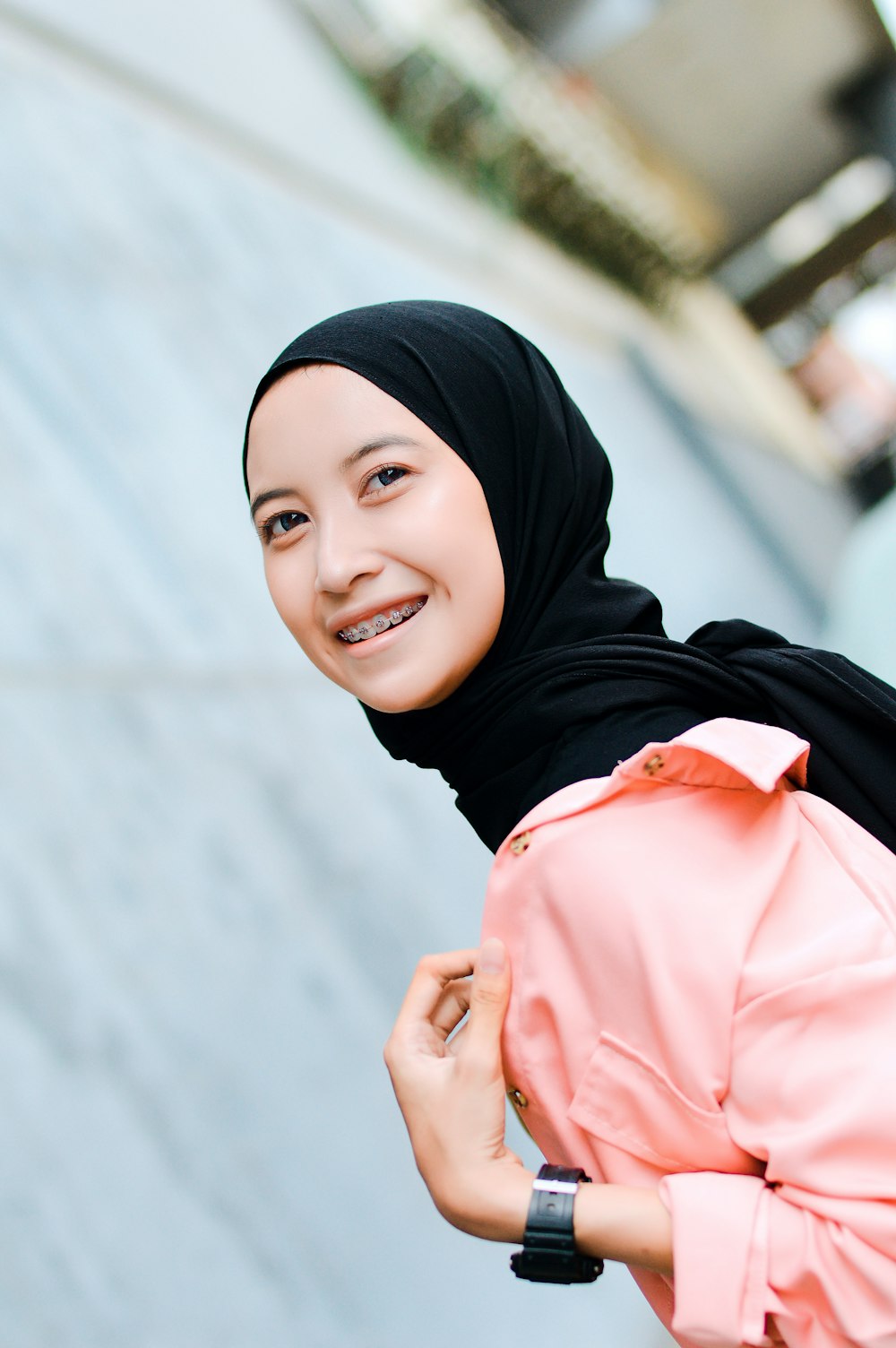 a woman in a hijab smiles at the camera