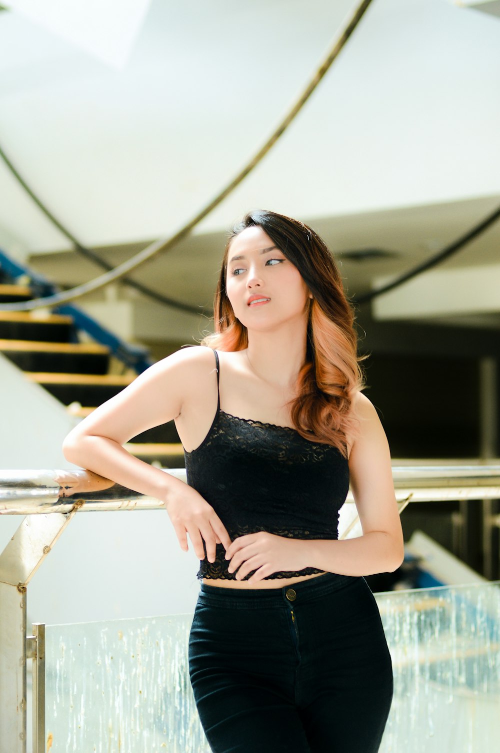 a woman in a black top leaning against a railing