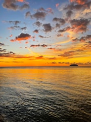 A vibrant sunset sky with deep reds and oranges over a calm sea.