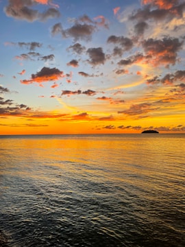 A vibrant sunset sky with deep reds and oranges over a calm sea.