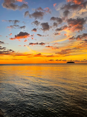 A vibrant sunset sky painted in deep reds and oranges over a calm sea.
