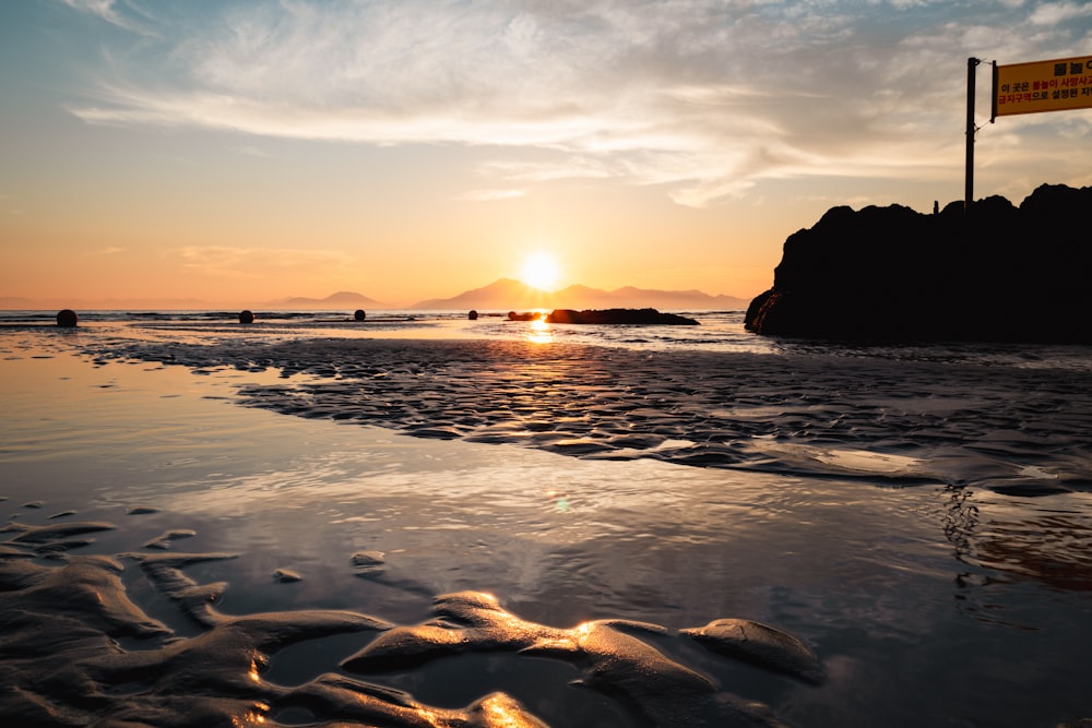 the sun is setting over the water at the beach