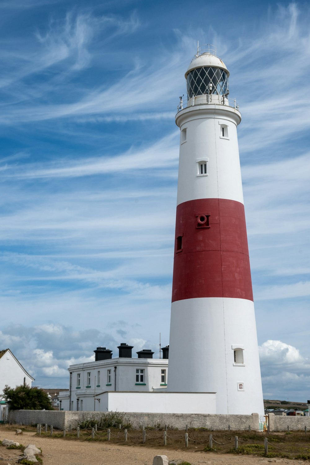 a red and white light house sitting on top of a sandy beach