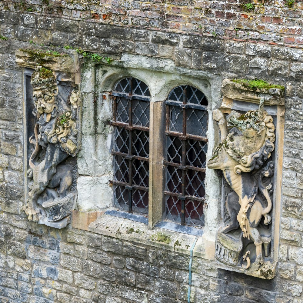 a stone building with two windows and a statue of a lion