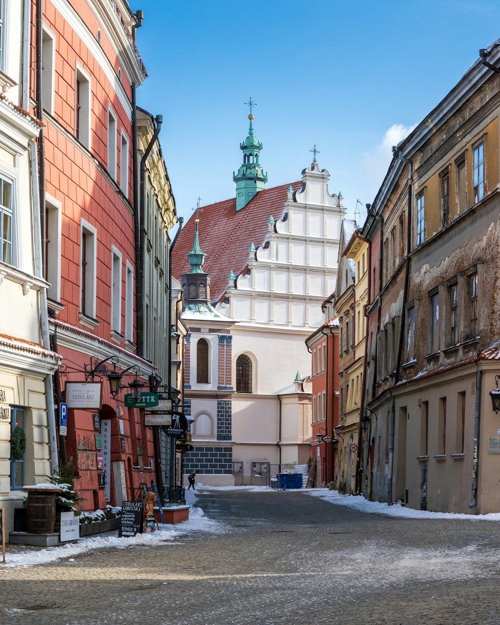 eine schmale Gasse mit Gebäuden und einem Glockenturm im Hintergrund