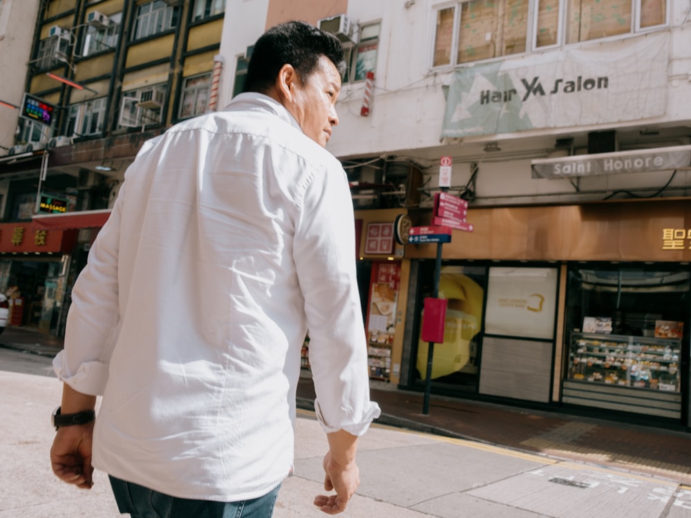 a man in a white shirt is walking down the street