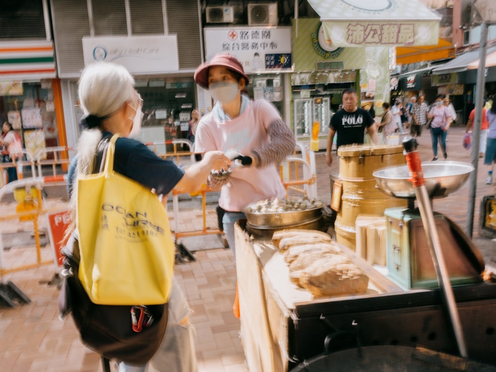 a woman in a face mask serving food to another woman