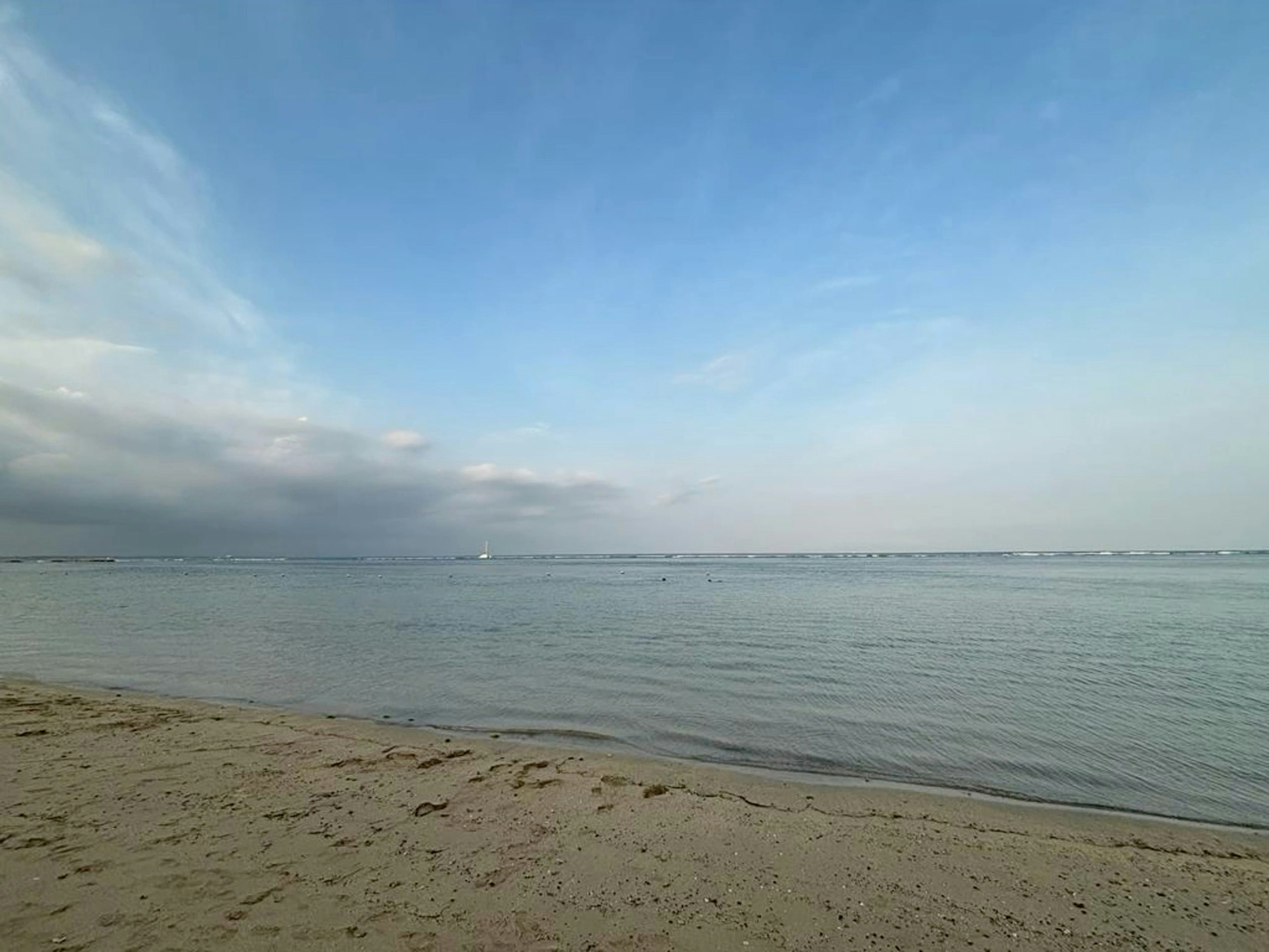 a sandy beach with a body of water in the distance, Nusa Dua Beach Bali