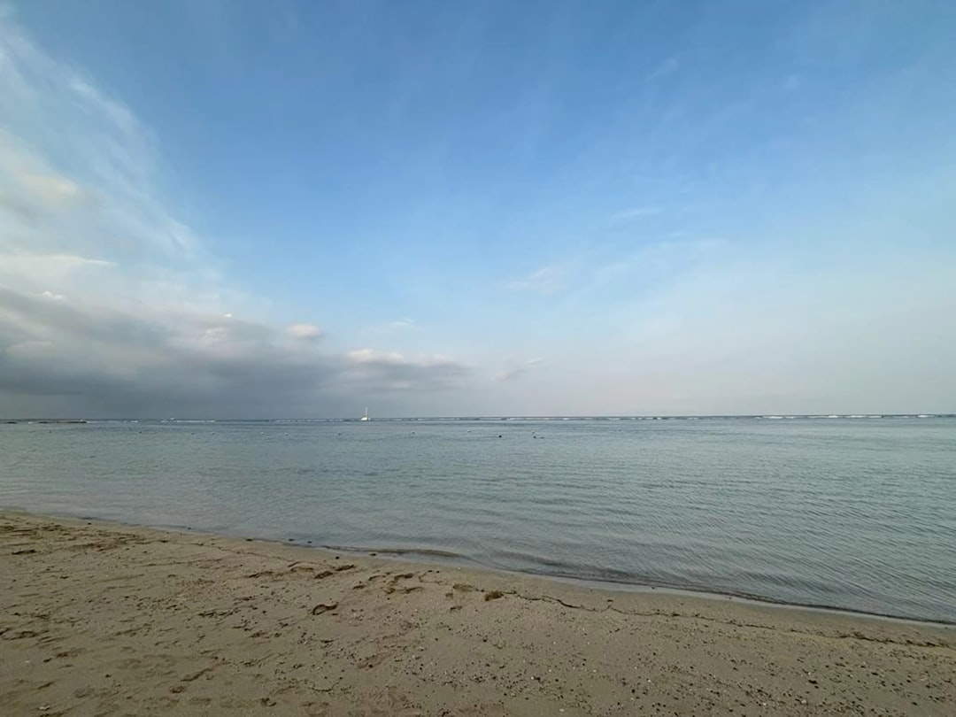 a sandy beach with a body of water in the distance, Nusa Dua Beach Bali