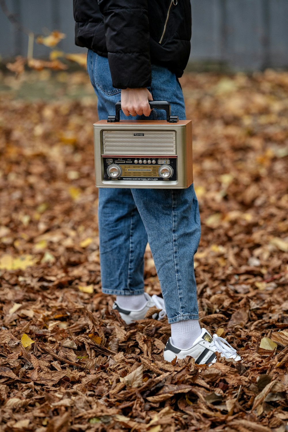 a person standing in leaves holding a radio